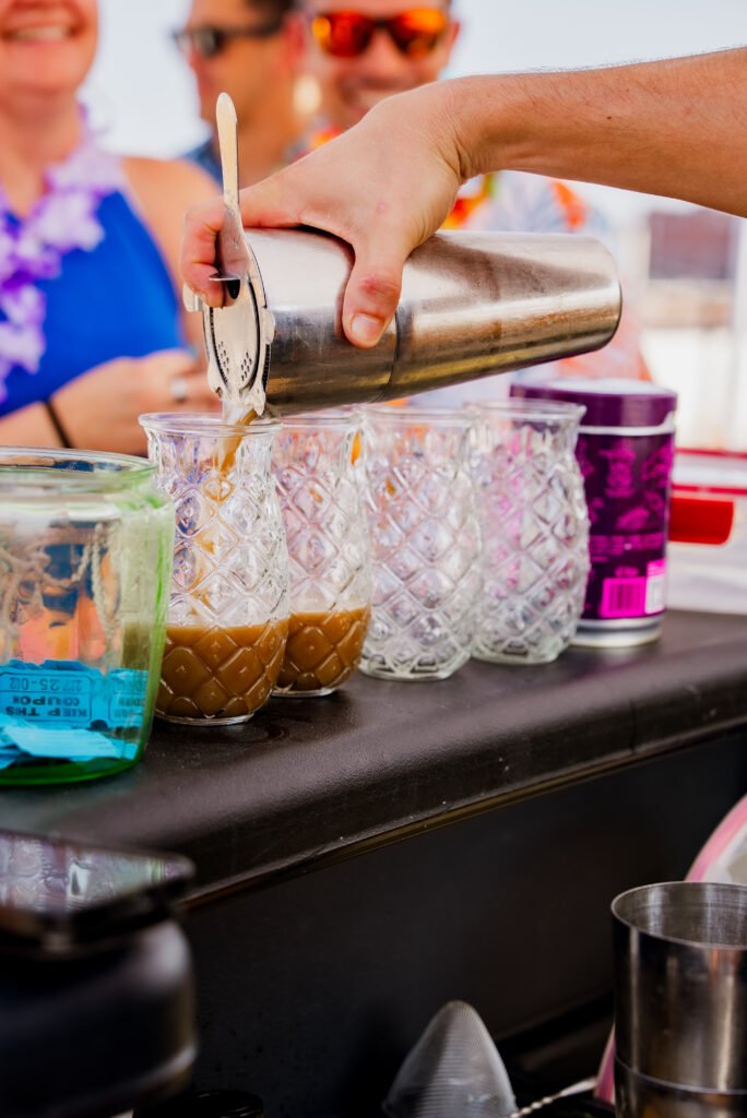 A cocktail strained from a shaker into pineapple glasses