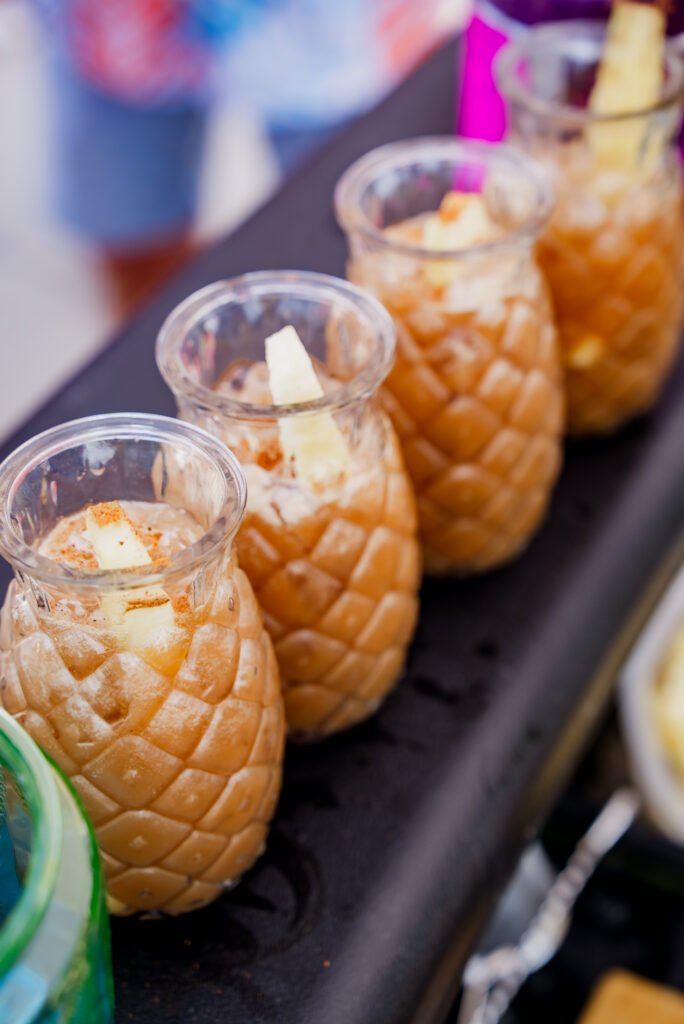 A row of finished cocktails in pineapple glasses