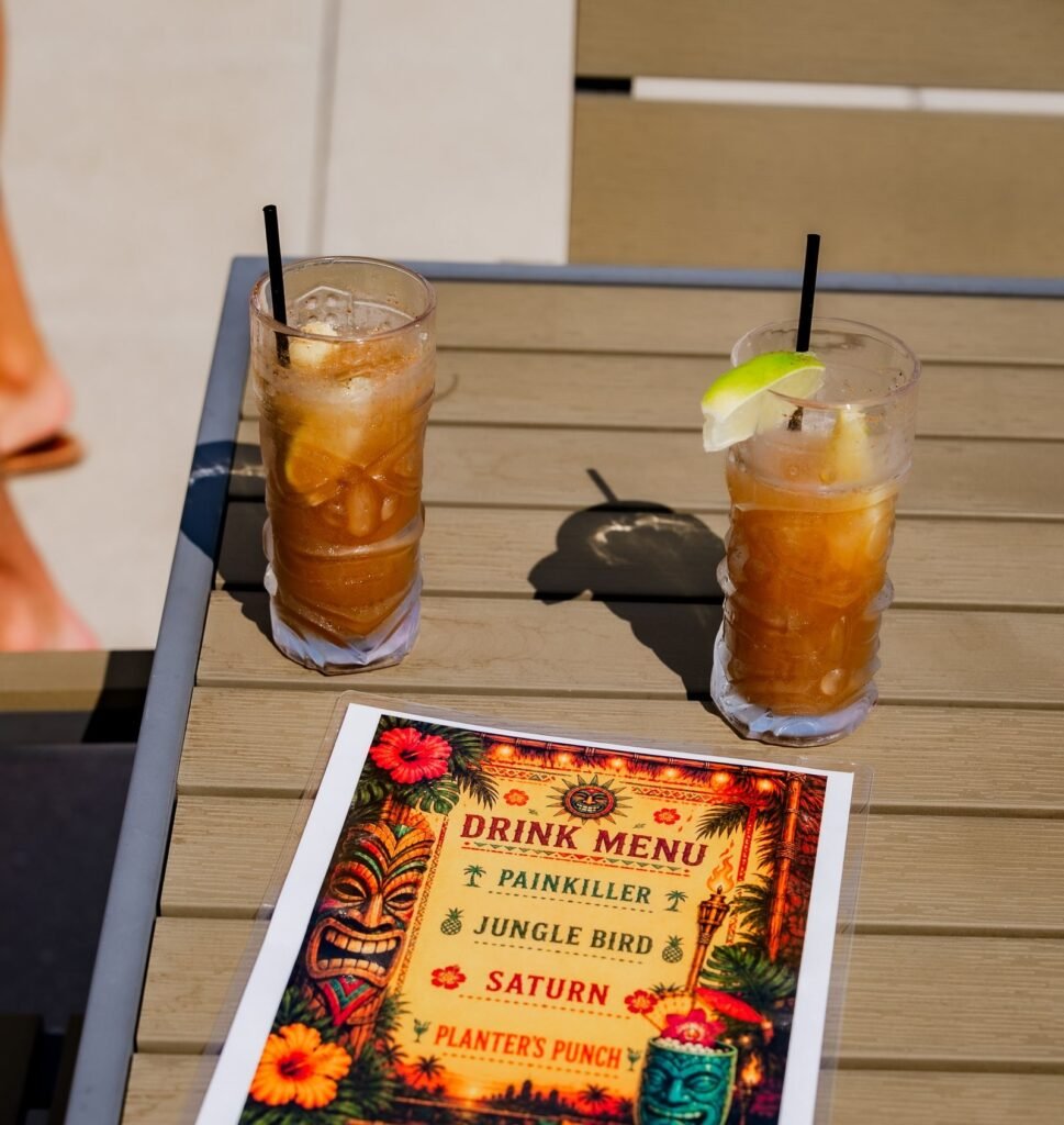 Two cocktails on a patio table beside a printed drink menu